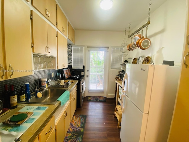 kitchen with stainless steel gas range oven, dark wood-style flooring, a sink, backsplash, and freestanding refrigerator