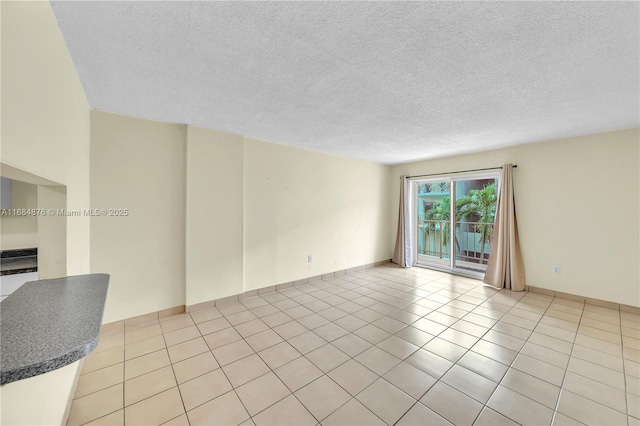 empty room with a textured ceiling and light tile patterned floors