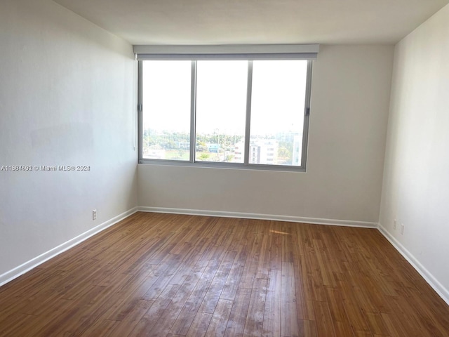 empty room with dark hardwood / wood-style flooring and plenty of natural light