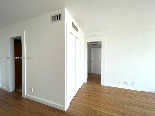 hall featuring visible vents, baseboards, and wood finished floors