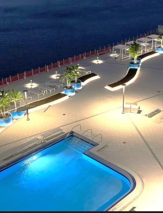 pool at night featuring a community pool