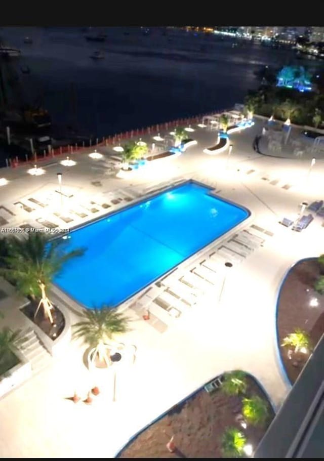 view of swimming pool featuring a patio and a water view