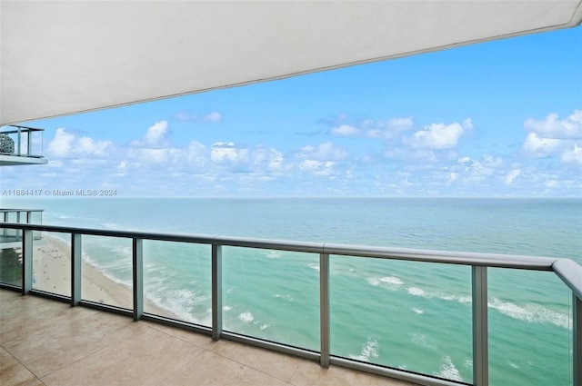 balcony with a water view and a view of the beach