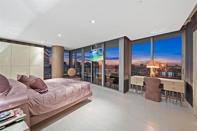 bedroom featuring a wall of windows and light hardwood / wood-style flooring