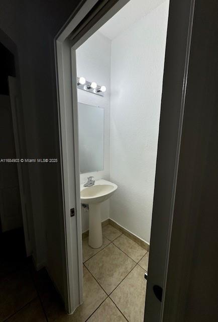 bathroom featuring tile patterned flooring, baseboards, and a sink