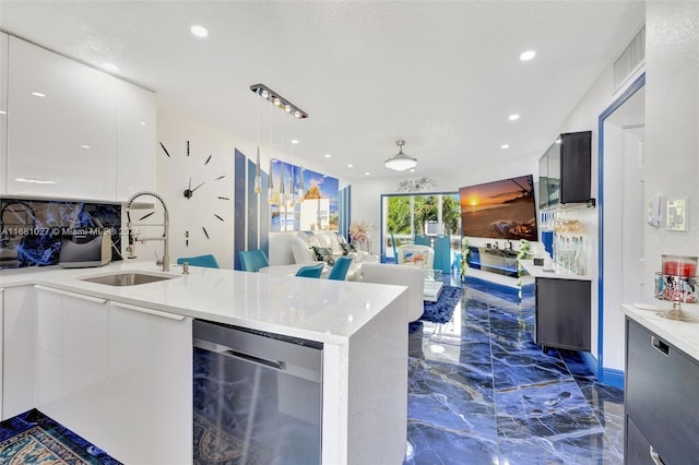 kitchen with white cabinets, light stone counters, dishwasher, decorative light fixtures, and sink