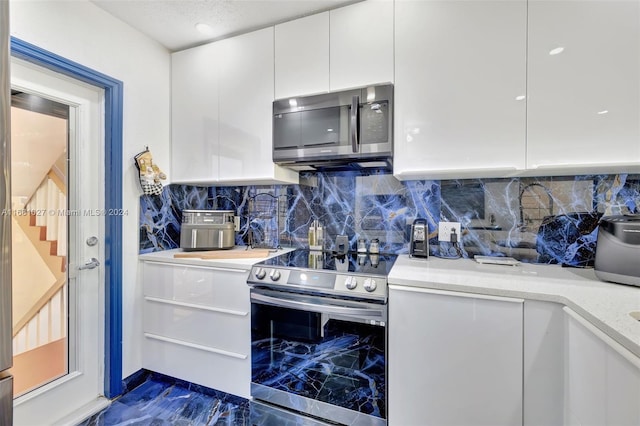 kitchen featuring white cabinetry, light stone counters, stainless steel appliances, and tasteful backsplash