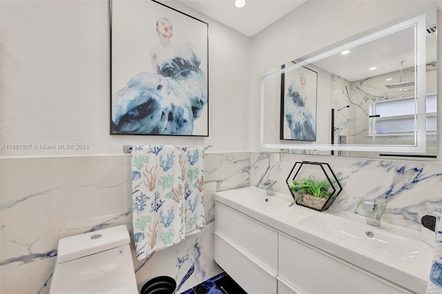 bathroom with tile walls, vanity, a shower, and toilet