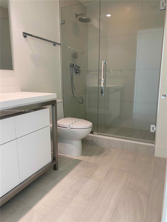 bathroom featuring vanity, a shower with shower door, toilet, and tile patterned flooring