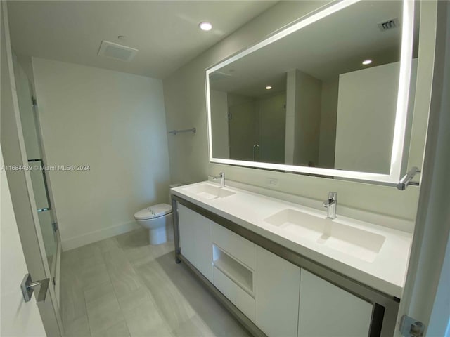 bathroom featuring vanity, a shower with shower door, and toilet