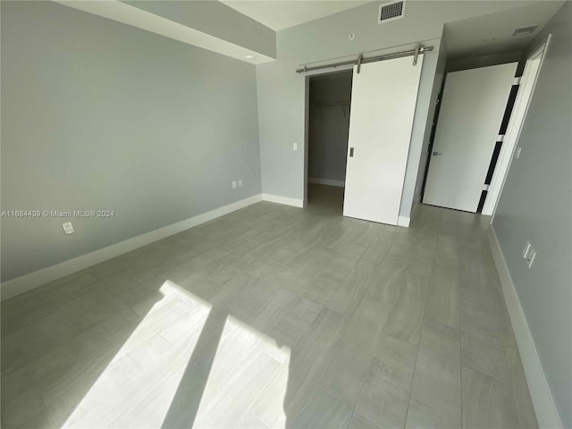 unfurnished bedroom featuring a closet, a walk in closet, and a barn door