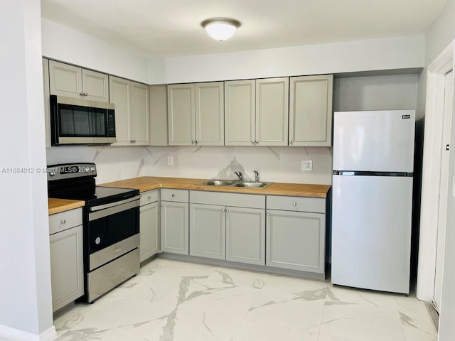 kitchen with backsplash, stainless steel appliances, wood counters, and sink