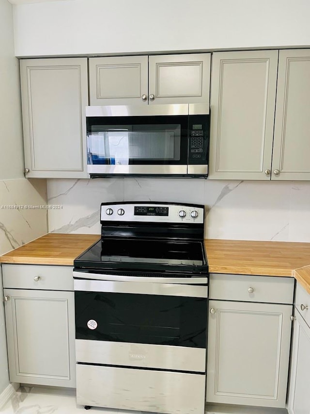 kitchen with butcher block counters, appliances with stainless steel finishes, decorative backsplash, and gray cabinets