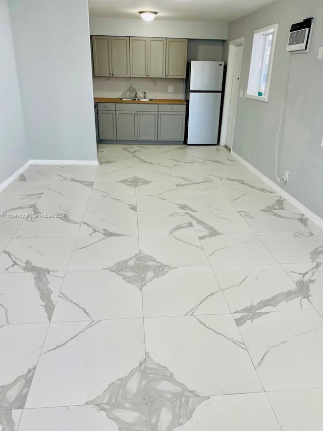 kitchen with an AC wall unit, sink, and fridge