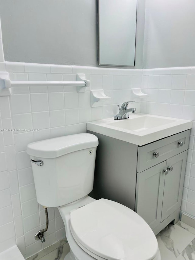 bathroom with toilet, vanity, and tile walls