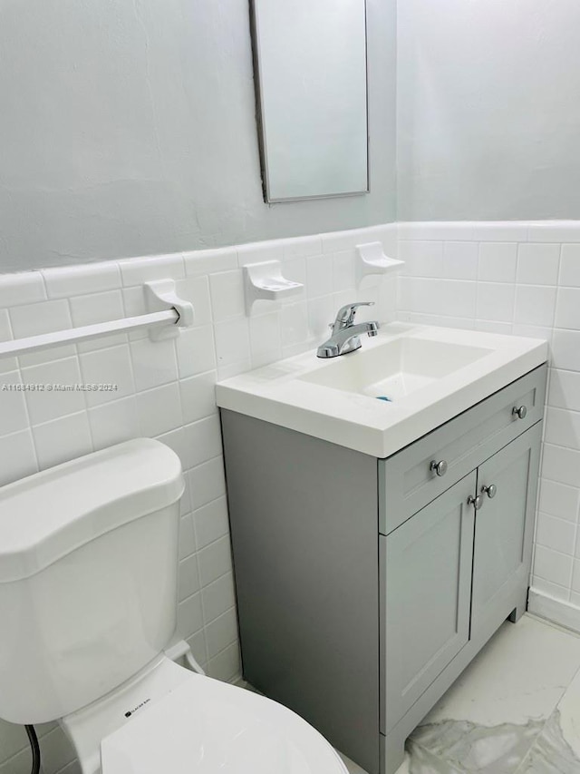 bathroom featuring vanity, toilet, and tile walls