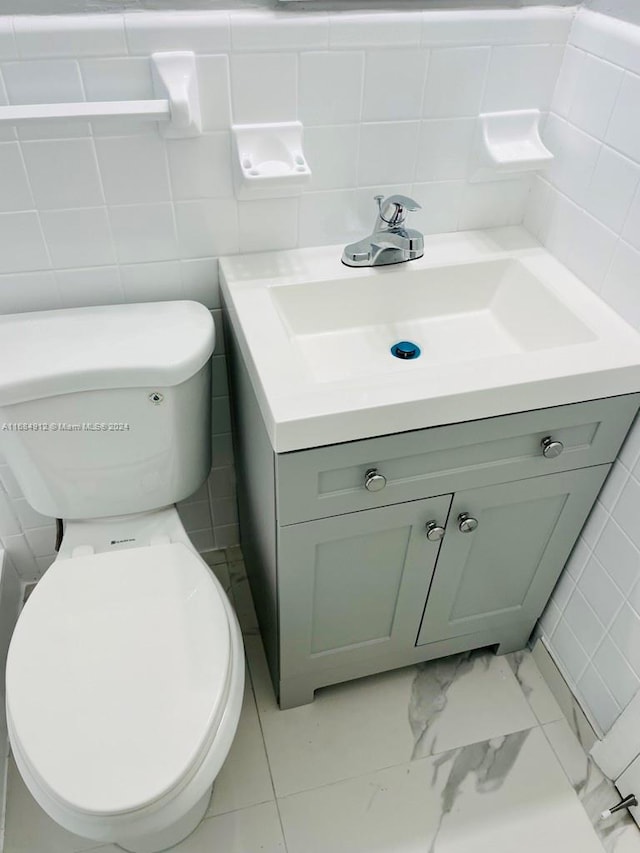 bathroom with vanity, toilet, tile walls, and decorative backsplash