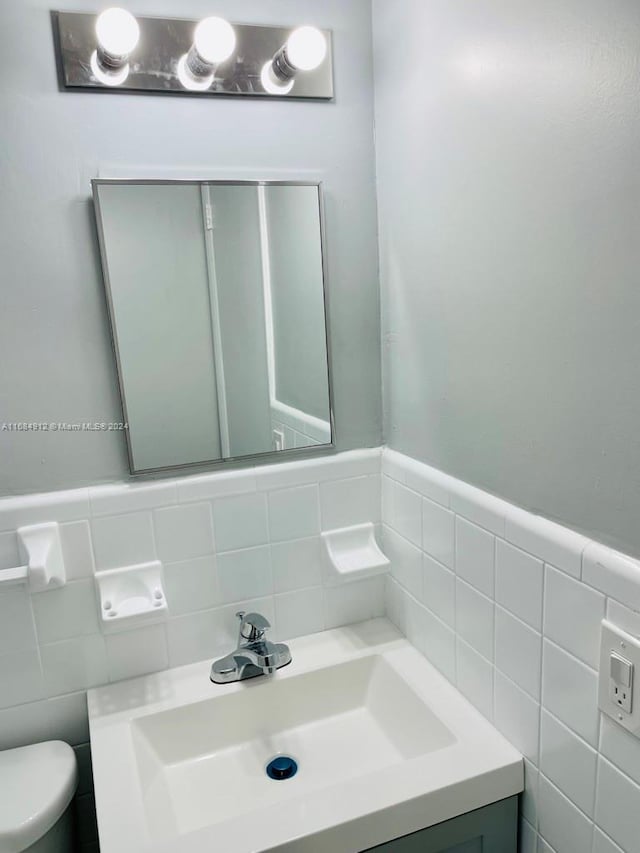 bathroom featuring vanity, toilet, and tile walls