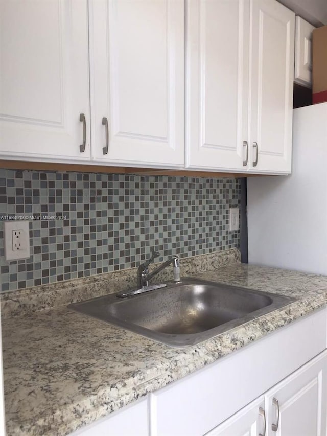 kitchen with decorative backsplash, white cabinetry, and sink