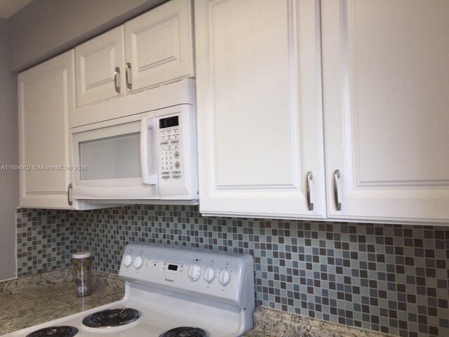 room details featuring white cabinets, light stone countertops, tasteful backsplash, and white appliances