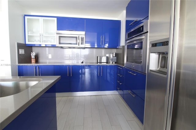 kitchen featuring decorative backsplash, appliances with stainless steel finishes, and blue cabinets