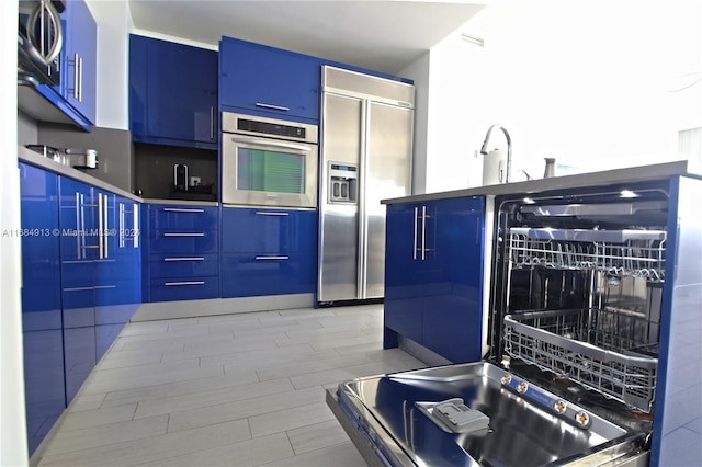 kitchen featuring appliances with stainless steel finishes, blue cabinets, and sink