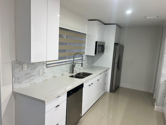 kitchen with sink, white cabinetry, light tile patterned floors, appliances with stainless steel finishes, and tasteful backsplash