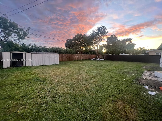 9520 Lisa Rd, Cutler Bay, FL 33157 - yard at dusk with a fenced backyard, a storage shed, and an outbuilding