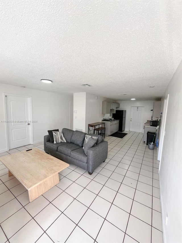 living room with a textured ceiling and light tile patterned floors