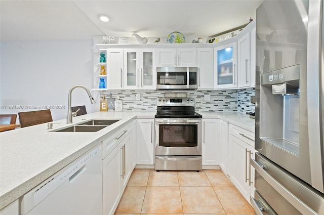 kitchen featuring sink, stainless steel appliances, white cabinets, decorative backsplash, and light tile patterned floors