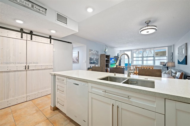 kitchen with sink, dishwasher, a barn door, and a textured ceiling