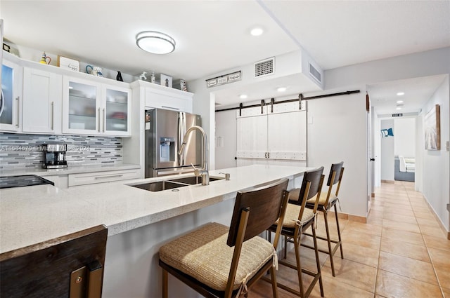 kitchen featuring white cabinetry, a barn door, sink, and a breakfast bar area