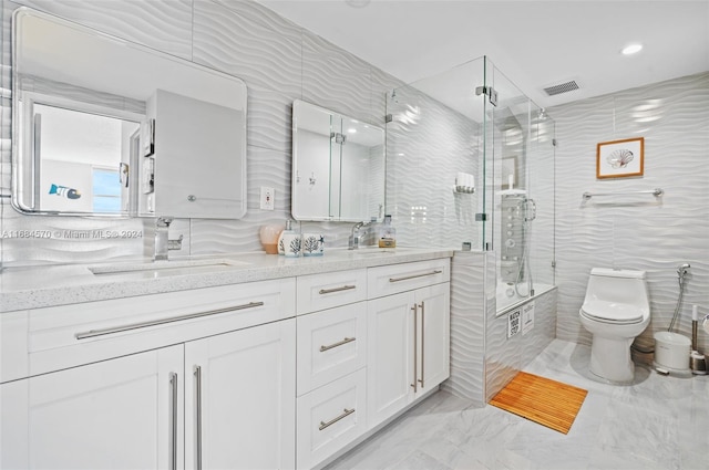 full bathroom with toilet, tile walls, vanity, and shower / bath combination with glass door