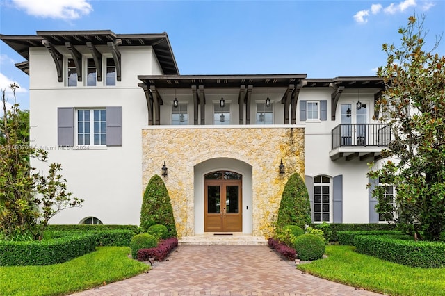 view of front of home with french doors, a balcony, and a front lawn