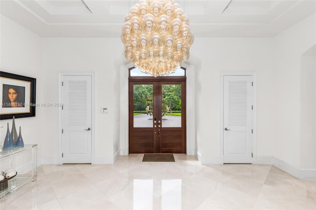 entryway with french doors, a notable chandelier, and a raised ceiling