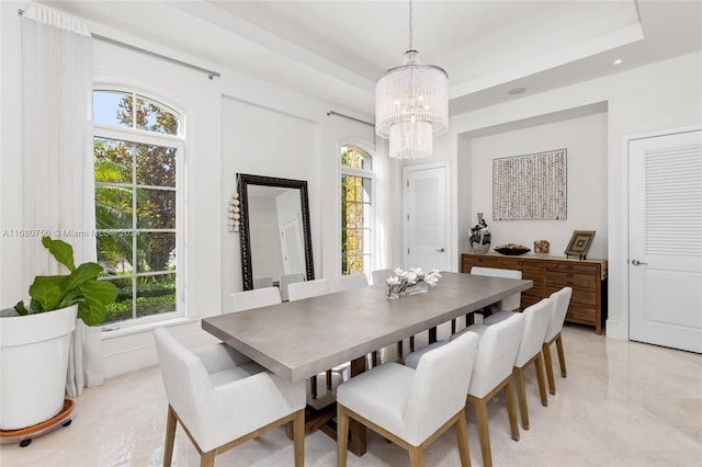 dining space featuring a wealth of natural light, an inviting chandelier, and a raised ceiling