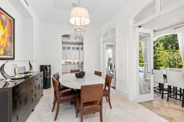 dining space with french doors, a notable chandelier, and a tray ceiling