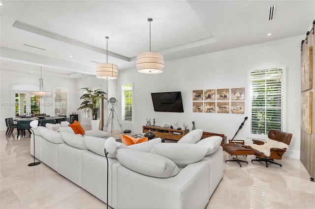 living room with a barn door and a tray ceiling