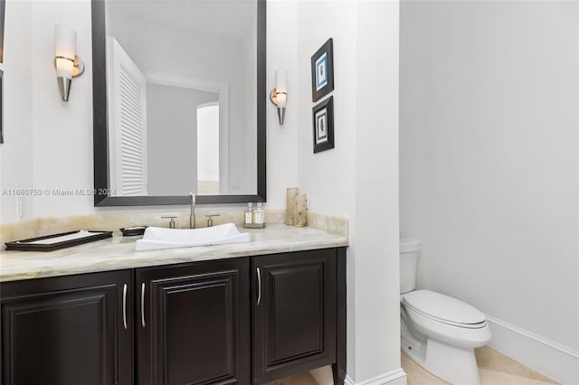 bathroom with toilet, vanity, and tile patterned flooring