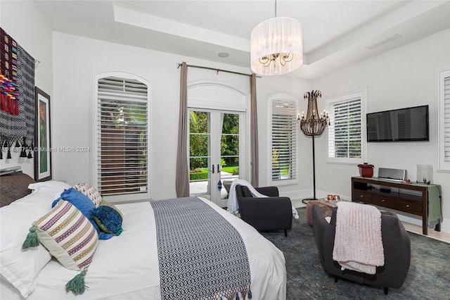 bedroom with access to outside, french doors, a chandelier, and a tray ceiling