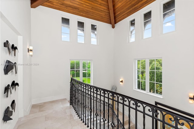 hall with wood ceiling, high vaulted ceiling, and beamed ceiling