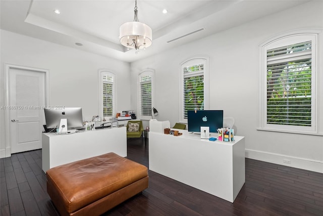 office area with dark wood-type flooring, a raised ceiling, and an inviting chandelier