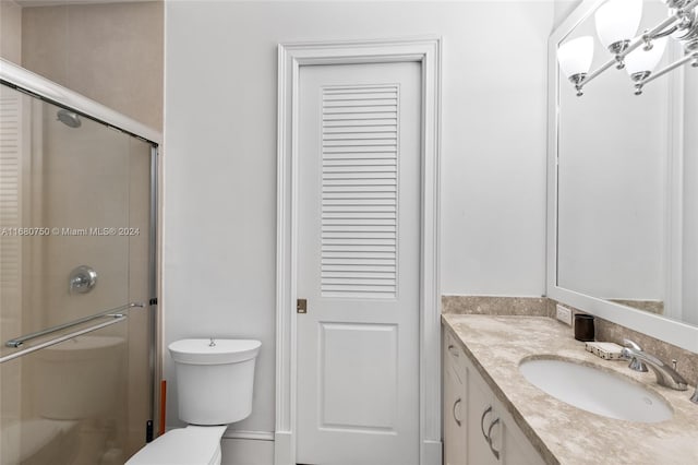 bathroom featuring toilet, vanity, and a shower with door