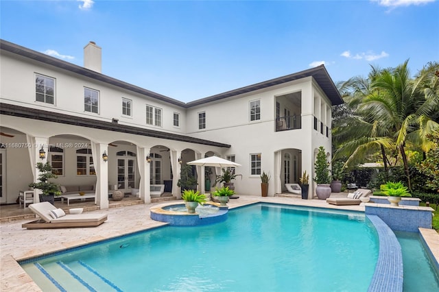 back of house featuring a swimming pool with hot tub, a patio, and a balcony