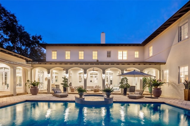 pool at twilight featuring an in ground hot tub, a patio area, and french doors