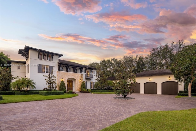 view of front of house featuring a balcony, a yard, and a garage