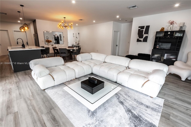 living room with sink, light hardwood / wood-style flooring, and a notable chandelier