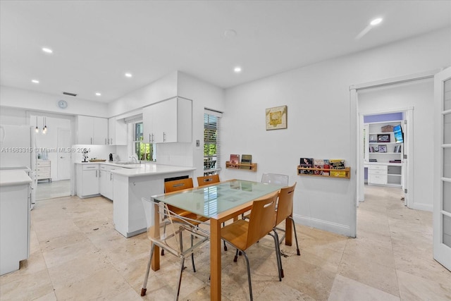 kitchen with kitchen peninsula, white cabinetry, white fridge, and tasteful backsplash