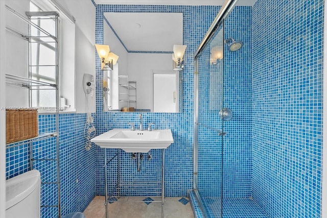 bathroom with sink, an enclosed shower, toilet, tile walls, and tile patterned flooring