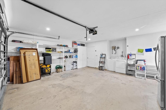 garage featuring independent washer and dryer, a garage door opener, and stainless steel fridge